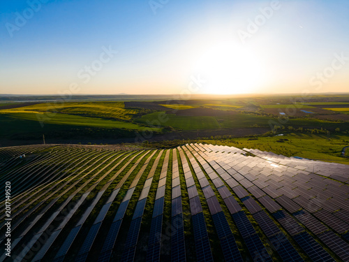 Photos Sunset over solar panels in a green field located in countryside, showing renewa
