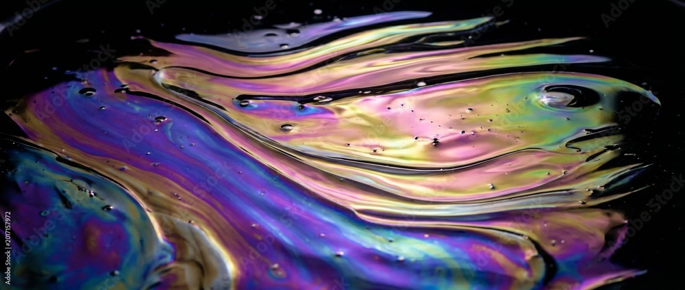 Obraz premium A mesmerizing display of swirling oil on the water's surface, creating a vibrant kaleidoscope of colors. The image captures the natural phenomenon.