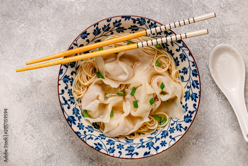Noodles and dumplings wontons in bowl with green onions
