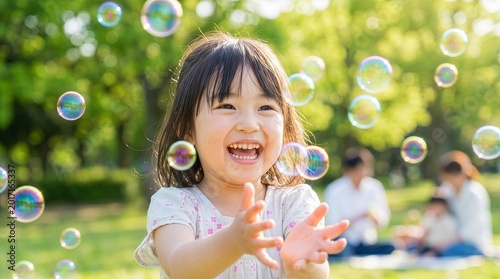 晴れた緑豊かな公園でシャボン玉を追いかける日本人の子供
