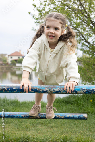 Happy Little Girl Balancing on Playground Pipes Outdoors – Active Child Enjoying Sports and Fresh Air
