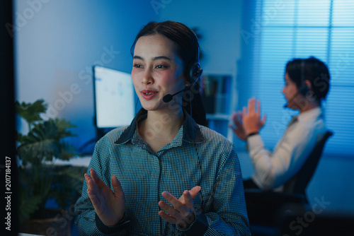 Gen z Asia young call center team or customer support service executive use computer and microphone headset work technical e commerce support in late night office. Telemarketing or sales job concept.