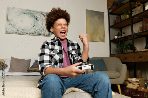 Quadro su tela Exciting gaming session brings joy and energy to a teenager at home
