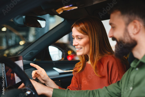 Couple exploring modern car infotainment system during dealership visit