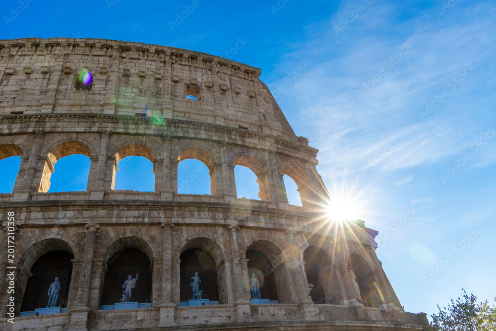 Obraz premium Famous Coliseum in Rome. Colosseum, or Coliseum. Sunset at huge Roman amphitheatre, Rome, Italy, Europe. Famous touristic place in the world and Europe. Beautiful blue sky background.
