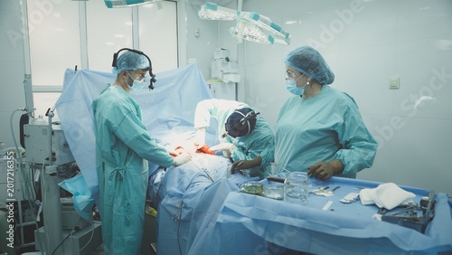 Team of medical doctors physicians surgeons two men with woman nurse operating emergency ambulance help plastic surgery teamwork three clinic workers operate cut out appendicitis health medicine job