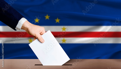 Quadro su tela Hand placing a ballot in ballot box with the Cape Verdean flag in the background