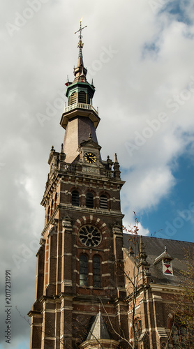 Historic 1892 brick church tower reaching into a cloudy blue sky.