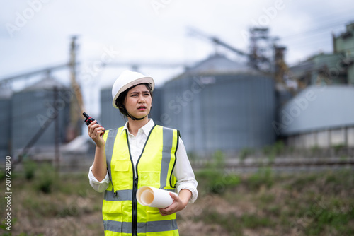 Canvastavla Female Engineer Wearing Safety Helmet and Vest Holding Documents and Walkie Talk