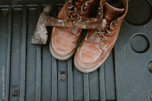 Worn leather work boots and a rustic axe resting on a textured surface
