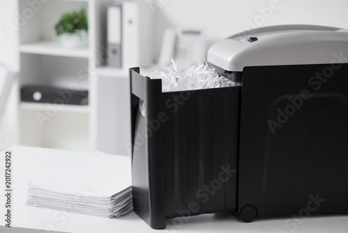 Принти на полотні Modern shredder with documents on desk in office, closeup