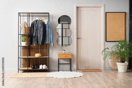 Interior of stylish hallway with mirror, table and coat rack