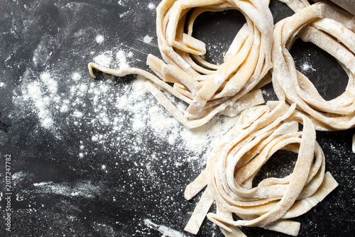 Konstfotografi top view of homemade fettuccine pasta with negative space on black background