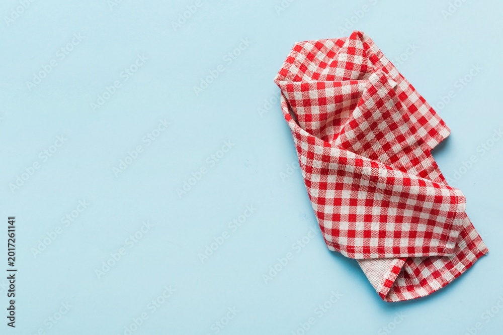 Fototapeta premium Red and white checkered tablecloth crumpled on light blue background