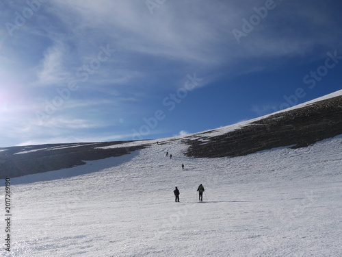 Konstfotografi Group of trekkers with backpacks hiking on a steep rocky mountain trail in the Himalayas under a clear blue sky
