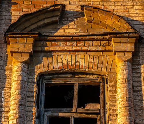 The wall of an old brick building with a broken window.