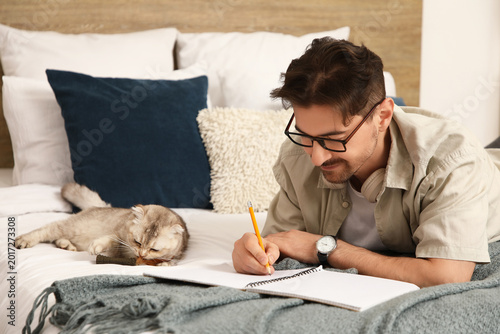 Young man writing in notebo...