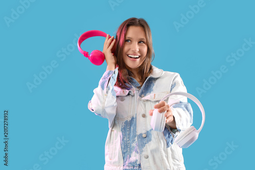 Happy young woman with different modern headphones on blue background