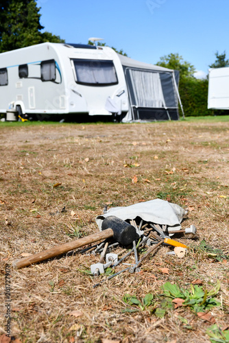Caravan Park with tools used to set up awnings or tents lying on very dry ground on a summers day, mallet and tent pegs ready to set up holiday home for family break.
