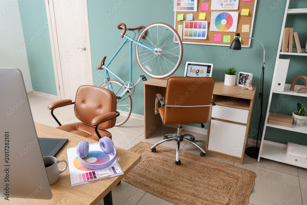 Fototapeta premium Interior of graphic designer's office with desks and bicycle