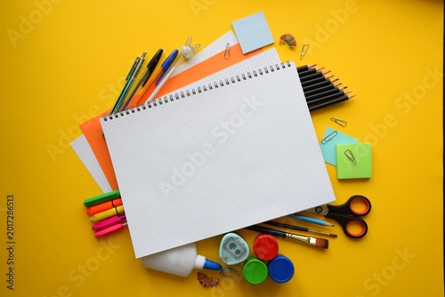 Blank Open Notebook Surrounded by Colorful School Supplies on Yellow Background Top View