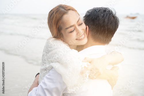 Canvas Print Young couple lifestyle hug on beach at sunset smiling woman embraces partner wit