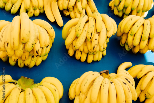Cuadro en lienzo Several bunches of bananas sit on  blue table in a market