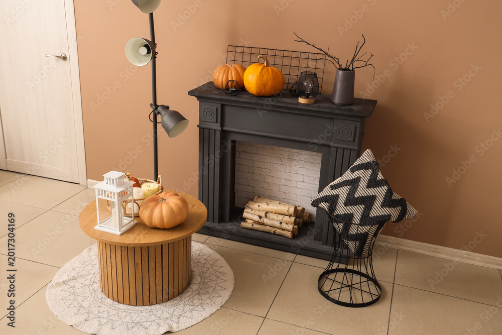 Fototapeta premium Black fireplace, coffee table, pillow and pumpkins in autumn living room