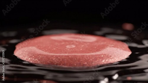 Red liquid drop hitting dark liquid surface causing ripples and splash, high speed photography, abstract macro detail