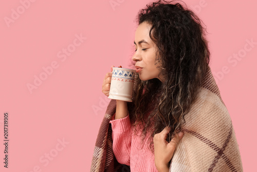 Photos Beautiful young African-American woman with cup of hot mulled wine and plaid on
