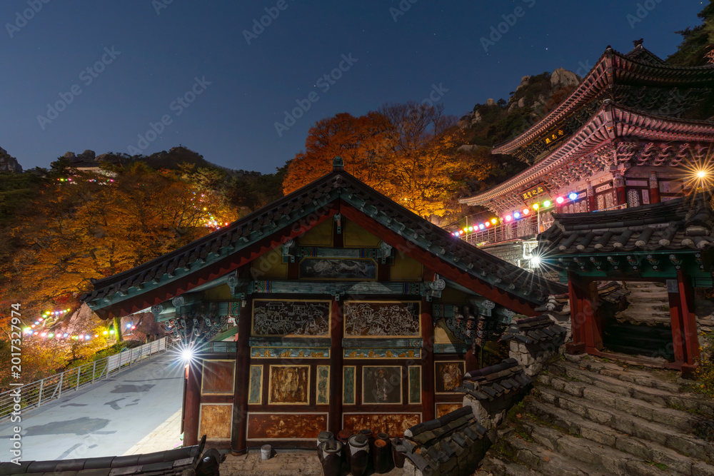 Obraz premium Enchanting night view of the historic Dobongsan Mangwolsa Temple illuminated by lanterns and starry sky during autumn season in Bukhansan National Park.