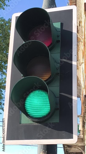 Traffic light switching from red to green at an urban intersection during sunny daytime, representing road safety, transportation flow, driving permission, and city traffic management