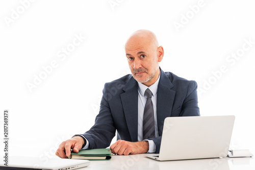 Confident businessman sitting at isolated background and using laptop