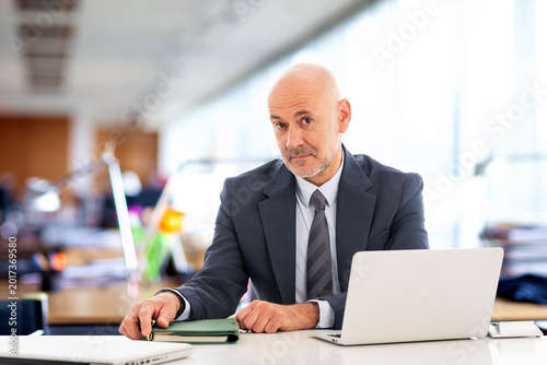Middle-aged professional businessman sitting at the office and using his laptop