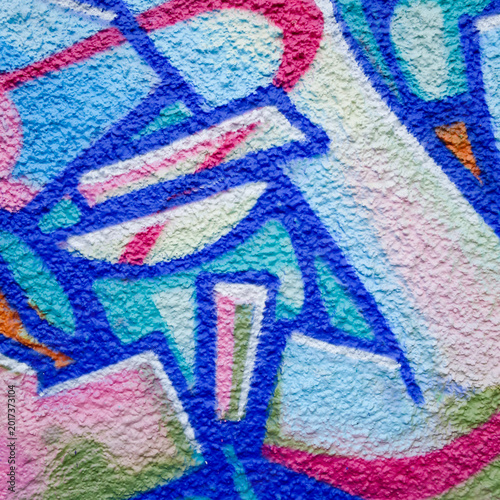 Gros plan sur un mur de graffiti texturé avec des couleurs bleu, rose et vert