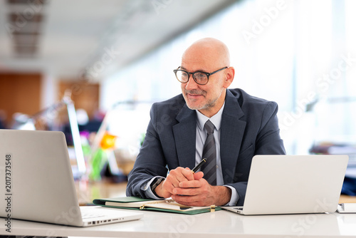 Middle-aged professional businessman sitting at the office and using his laptop