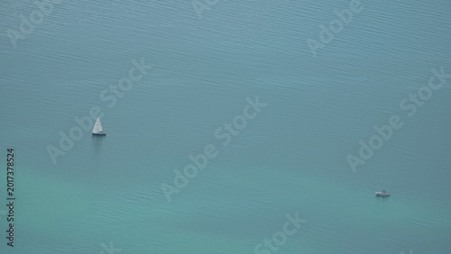 Aerial minimalist view of a sailboat and a motorboat on the turquoise waters of Lake Geneva, Switzerland