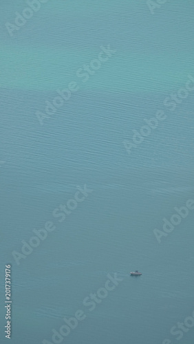 Solitary white sailboat on the vast turquoise waters of Lake Geneva, Switzerland - minimalist aerial view