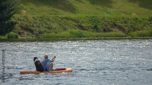 Femme faisant du stand-up paddle sur un lac avec son chien Border Collie