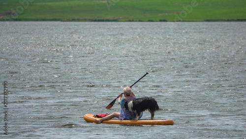 Femme faisant du stand-up paddle sur un lac avec son chien Border Collie