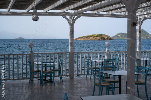 Foto Seaside view from a restaurant with tables and chairs facing the water and dista