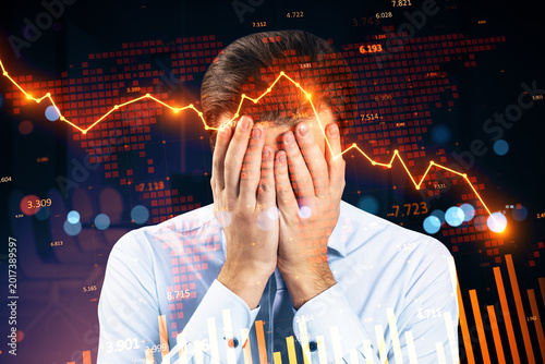 Businessman covering face amid glowing red downward stock chart and global market collapse background illustrating financial crisis impact.