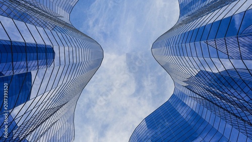 Photography Low angle view of 3D modern blue glass skyscrapers with curved facades under a c