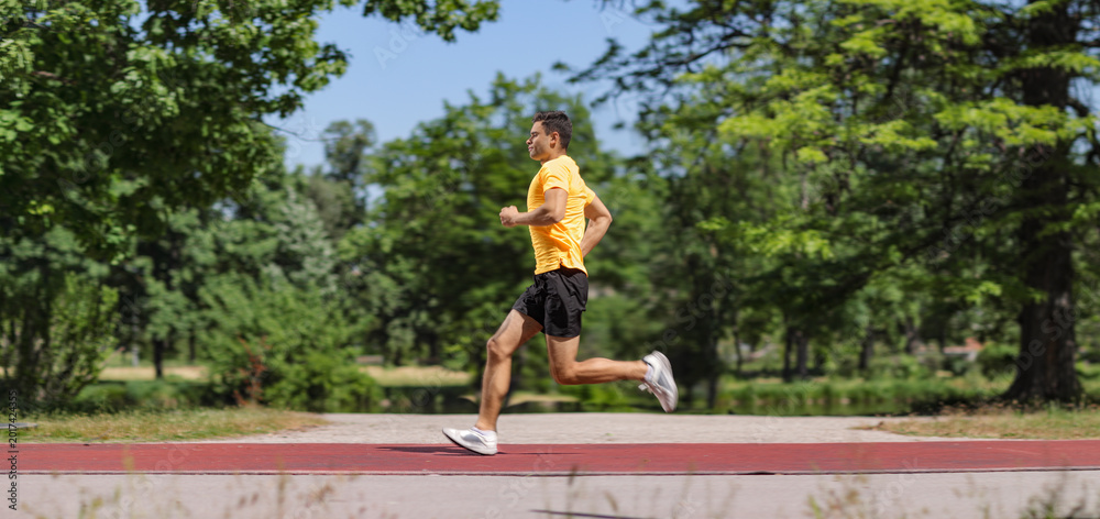 Fototapeta premium Athletic man jogging on a running track