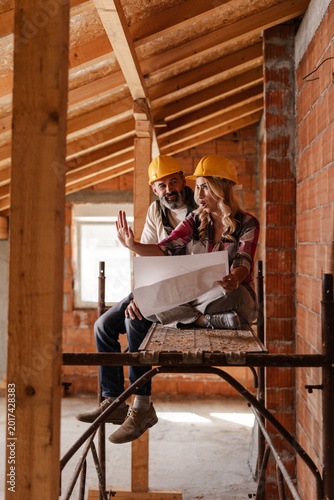 Couple Discuss Building Plans During Construction Inside a New Structure in a City Setting