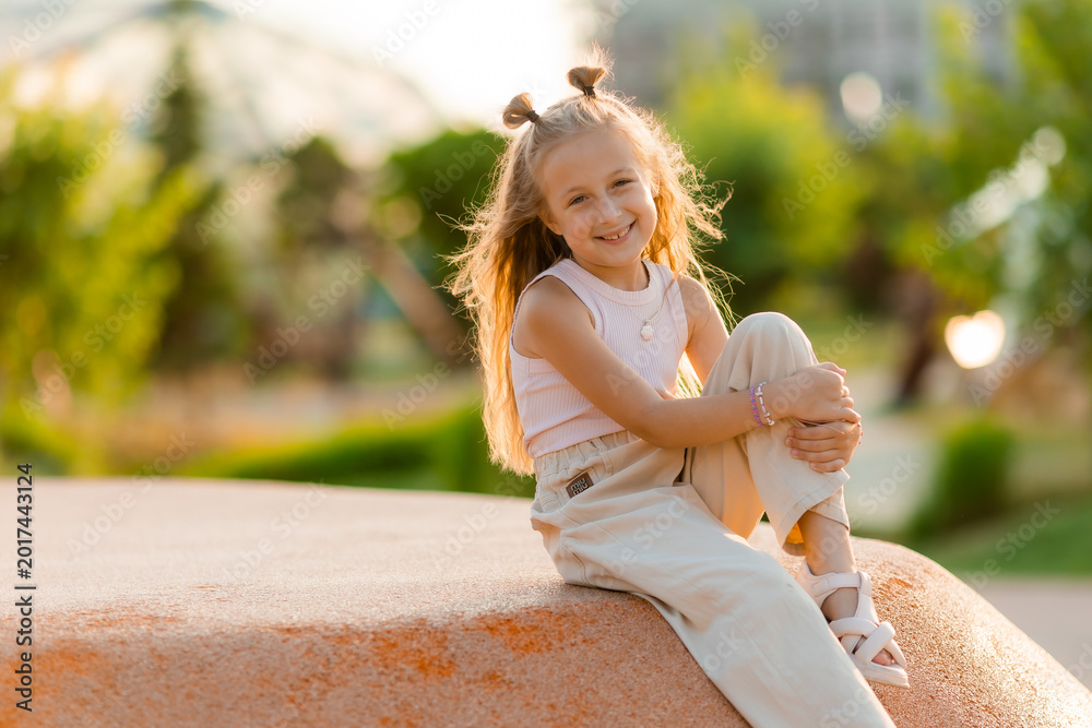 Naklejka premium little happy girl at a playground in the city in summer