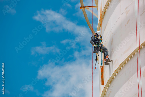 Foto Male worker rope access industrial working at height tank oil wearing harness, h