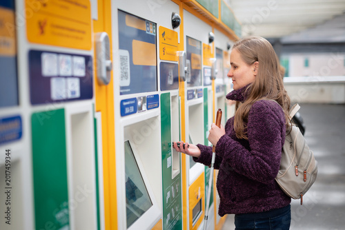 Visually impaired woman standing on the train station and buying ticket