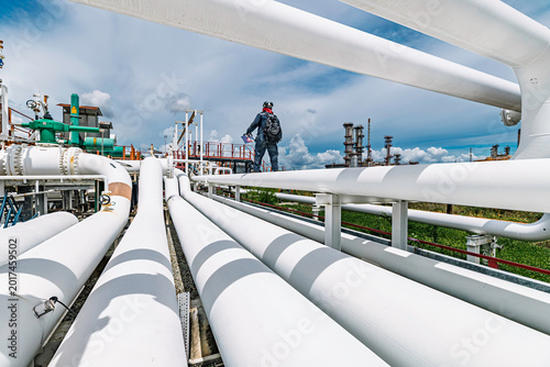 Male worker inspection at steel long pipes and pipe elbow in station oil factory during refinery valve of visual check record pipeline tank oil