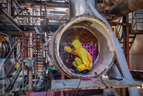Male workers use high-pressure water jets to clean splashing the dirt of tube boilers in industrial areas or toxic hazardous material